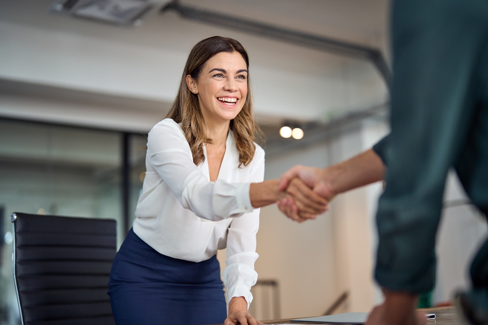 Professional woman shaking hands in an office setting, symbolising career growth and confidence